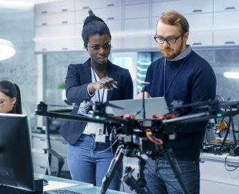 A group of researchers studying a drone in a laboratory.