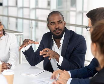 A group of people sit around a table with paperwork and documents