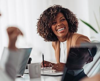 A person in a conference room smiles towards other people in the room