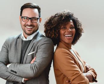 Two people pose in front of a grey background