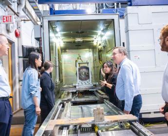 Un groupe de personnes se tient de part et d’autre d’une longue machine en métal