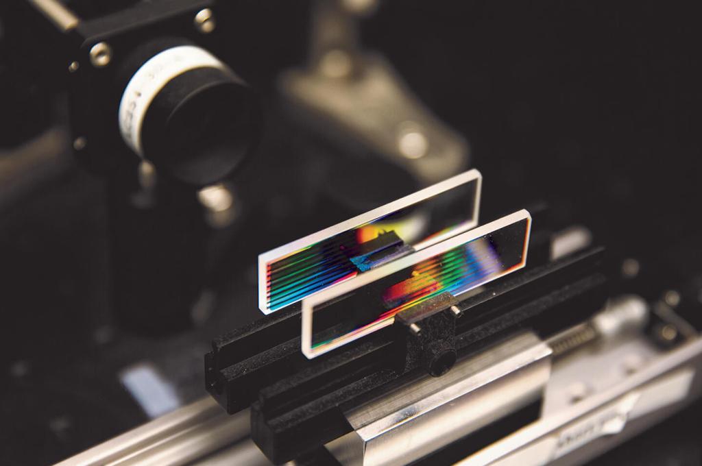 Deux petites lames de verre rectangulaires avec des lignes de plusieurs couleurs sont posées sur un support.