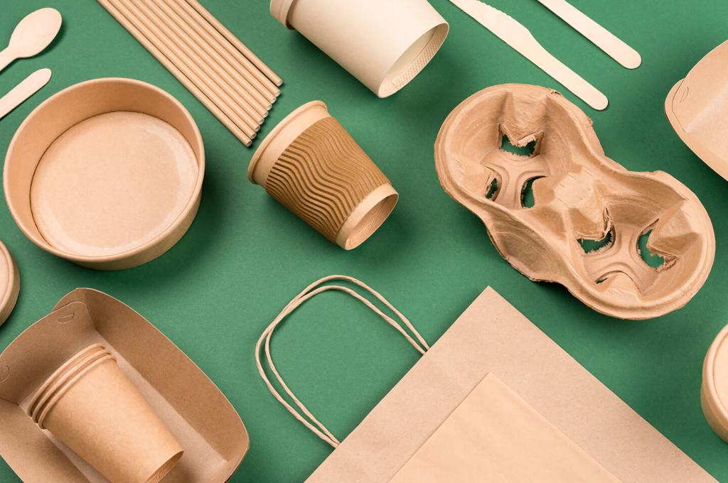 Brown paper cups, trays and bags arranged neatly on a green background.