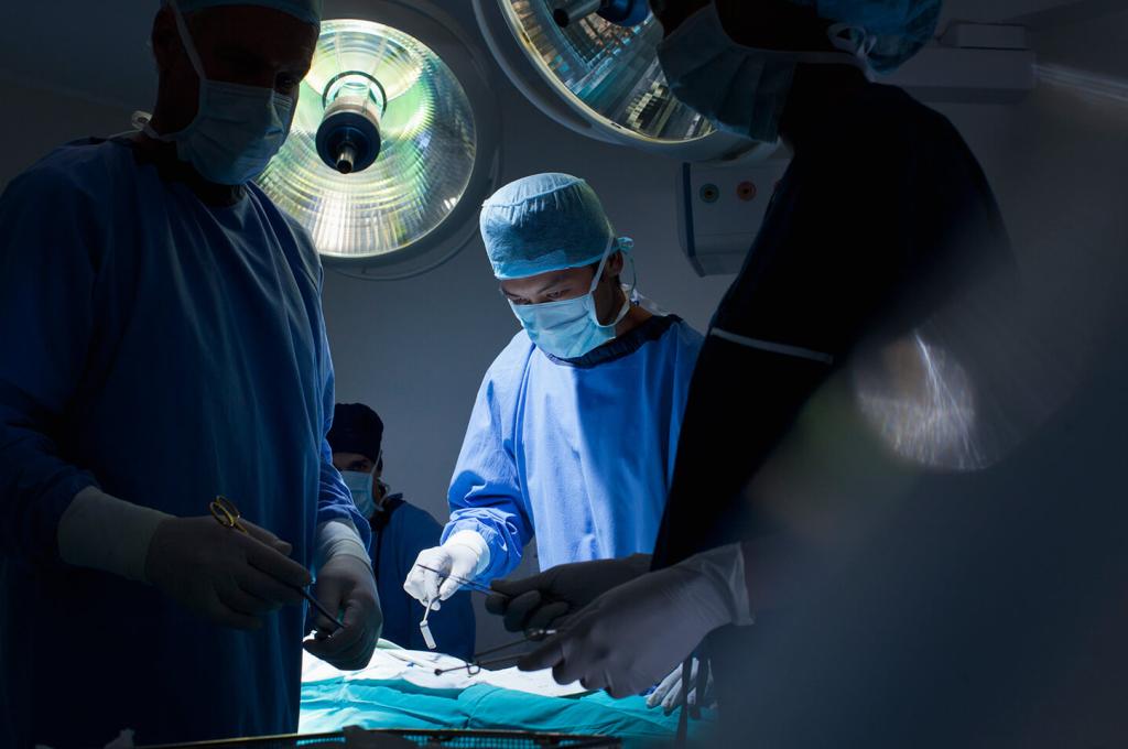 Several surgeons and nurses around an operating table.