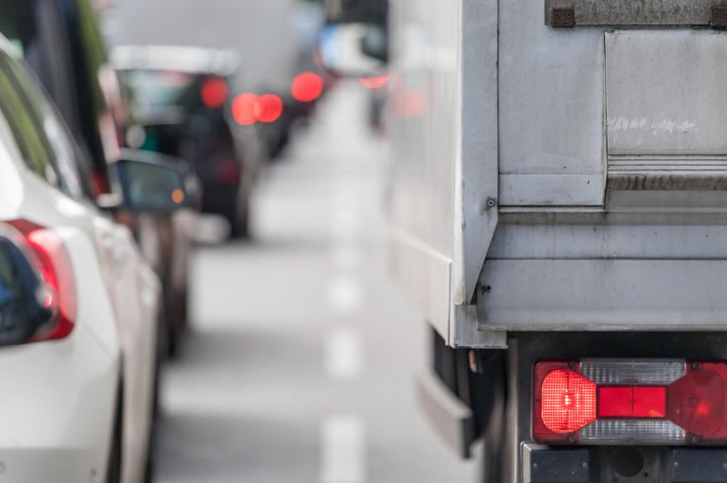 Photo en gros plan des feux arrière d'une voiture et d'un camion de transport à l'arrière d'une longue file de véhicules.
