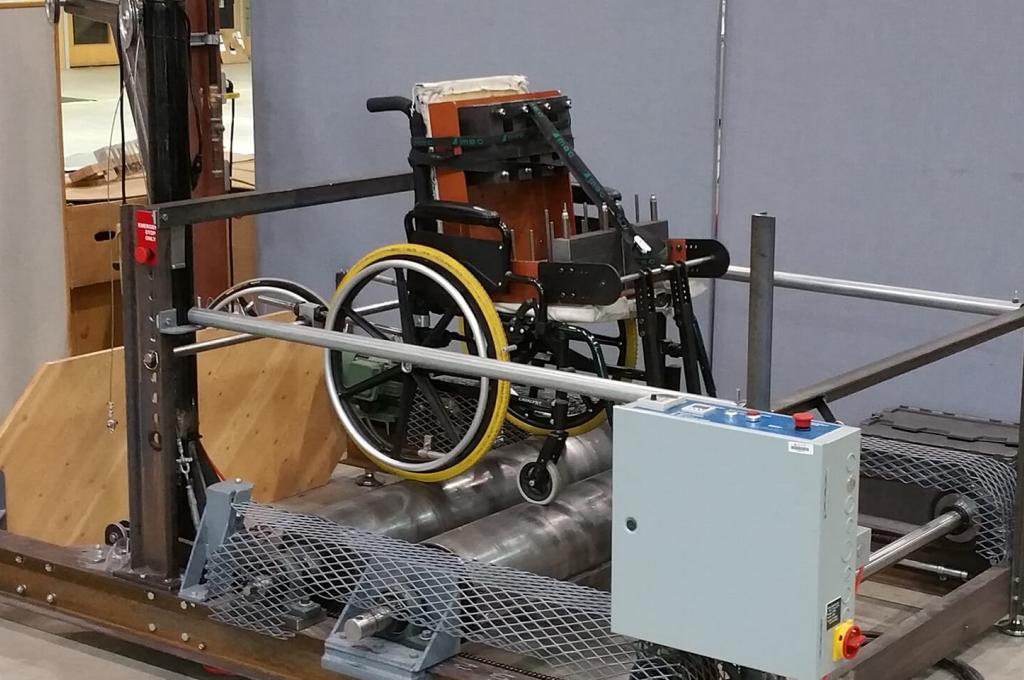 A wheelchair is strapped in testing equipment in a laboratory.