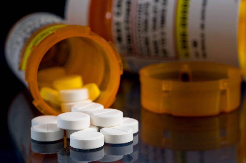 Prescription pill bottles tipped over with white tablets poured out