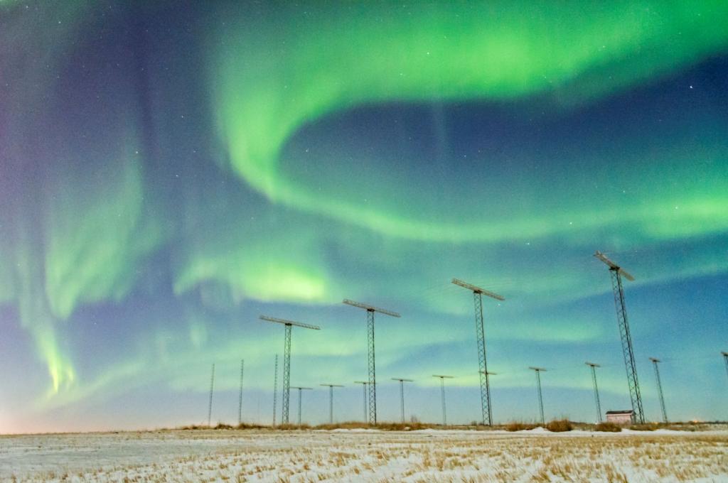 SuperDARN antennas with aurora borealis in the sky above.