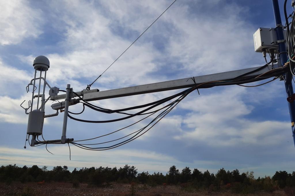 A metal arm equipped with research instruments extends from a tower overlooking a peat bog.