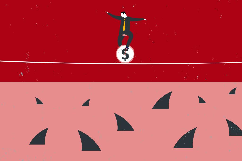 Illustration of a man in a grey suit sitting on a unicycle with a dollar sign on it. He is balancing on a tightrope and looking down at the shark fins darting out of the water below. The sharks are waiting for him to fall.