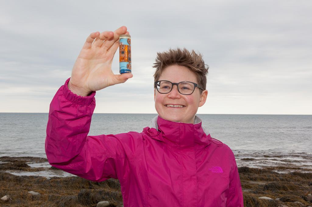 Dr. Franziska Broell holding a small container in front of an ocean view.
