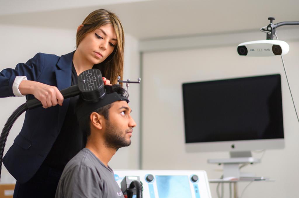 Faranak Farzan applies a device to the side of a seated man’s head