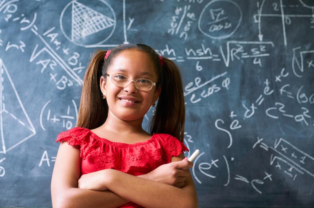 Pigtailed girl stands in front of chalkboard containing many mathematical