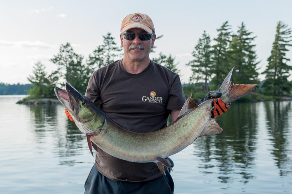 Image of Regan Thompson holding a fish with his two arms.
