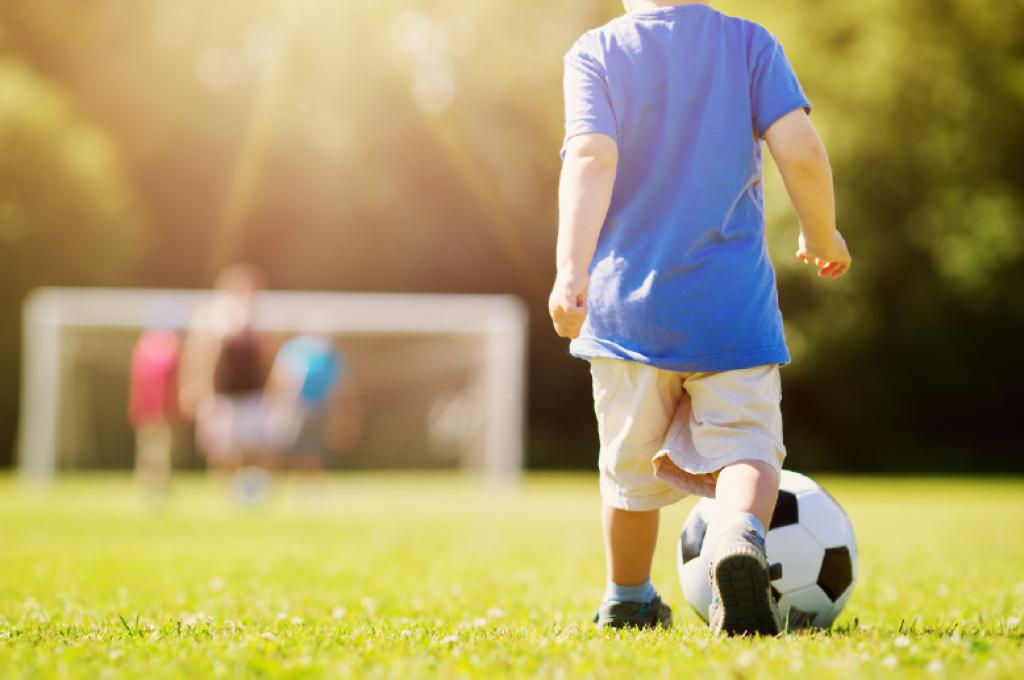 Un enfant botte un ballon de soccer vers un filet