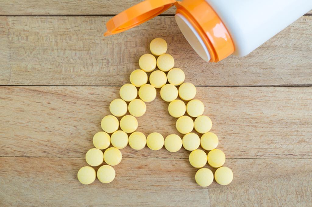 A bottle spills out yellow tablets in the form of the letter “A.”