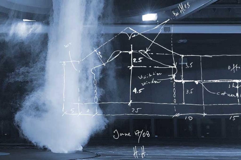 Simulation d’une tornade, telle une colonne de brouillard matinal, qui est propulsée du plafond d’un vaste tunnel noir. Un croquis à la main d’un tunnel aérodynamique recouvre partiellement l’image.