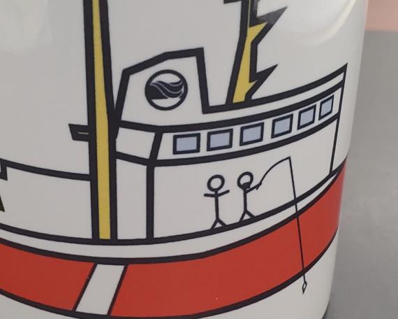 White mug with a child’s drawing depicting a stylized red and yellow boat.