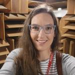 A person wearing a grey sweater posing for a photo, inside an anechoic chamber.