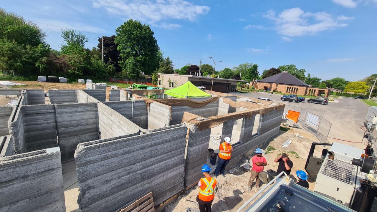 Top view of the cement walls of a fourplex with construction workers in foreground.